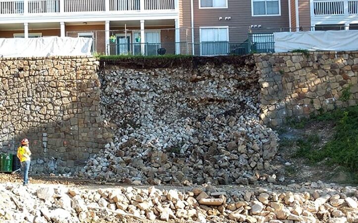 Failed stone retaining wall in front of apartment buildings.