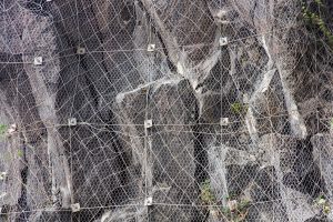 Slope of the mountain with a rockfall protection net preventing rocks falling on the road