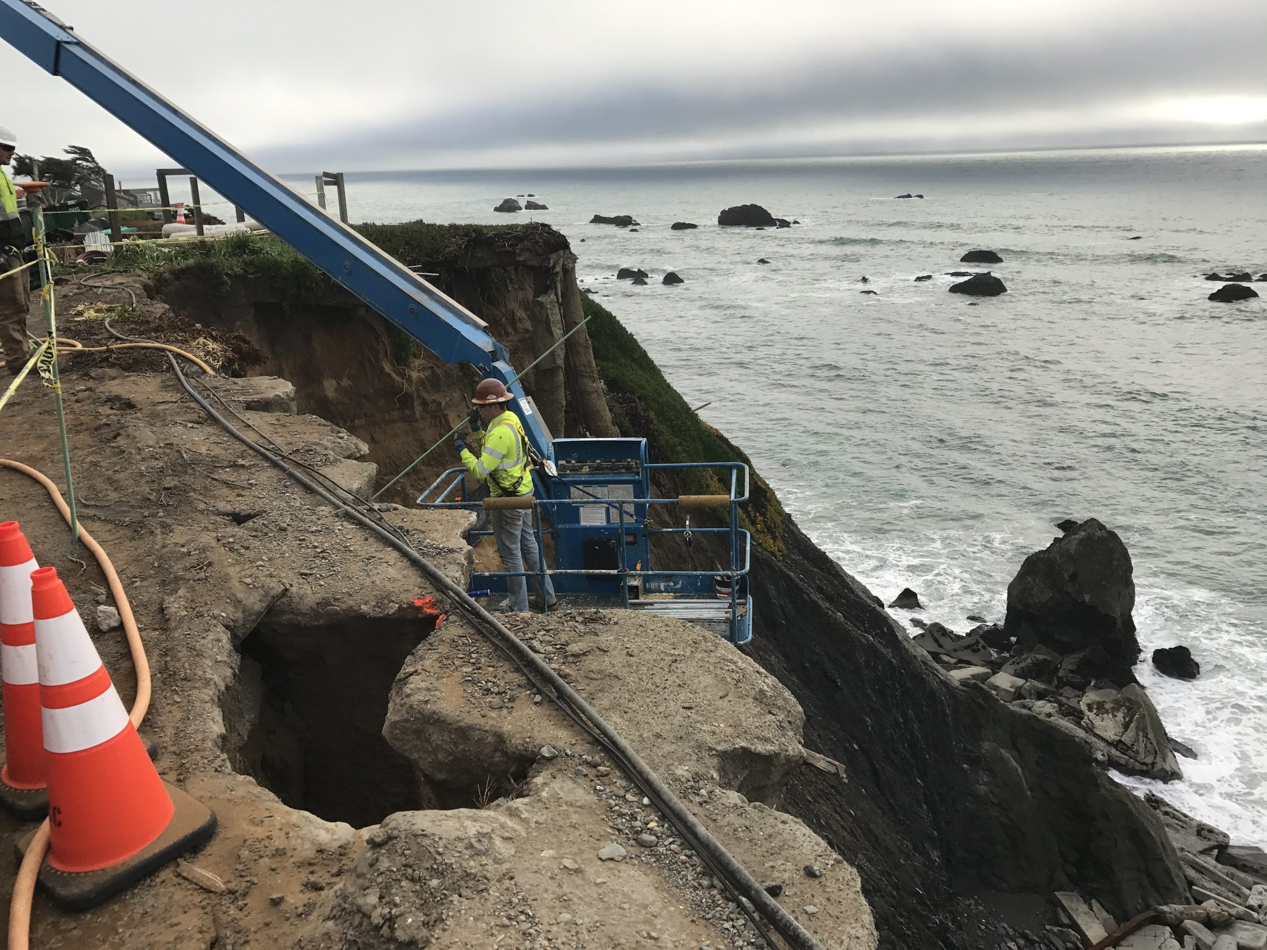 Crew working from a lift near a coastal cliffside.