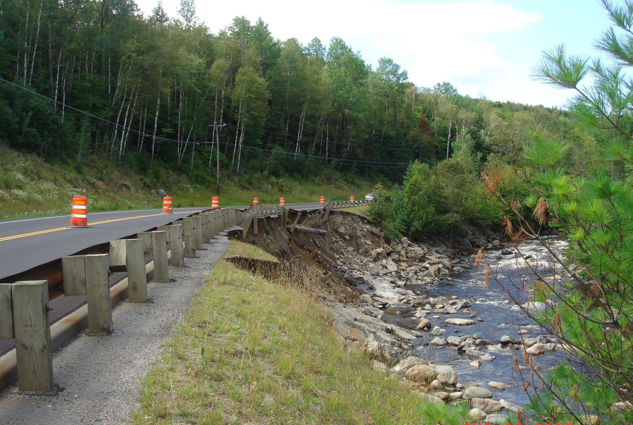 Eroded road shoulder next to a river.