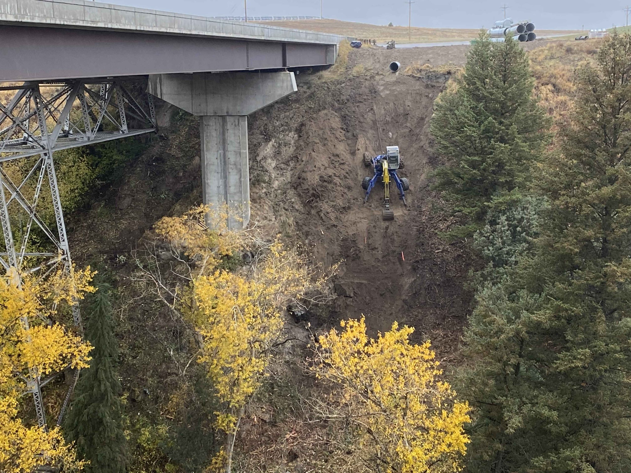Spider Excavator on Steep Slope Under Bridge