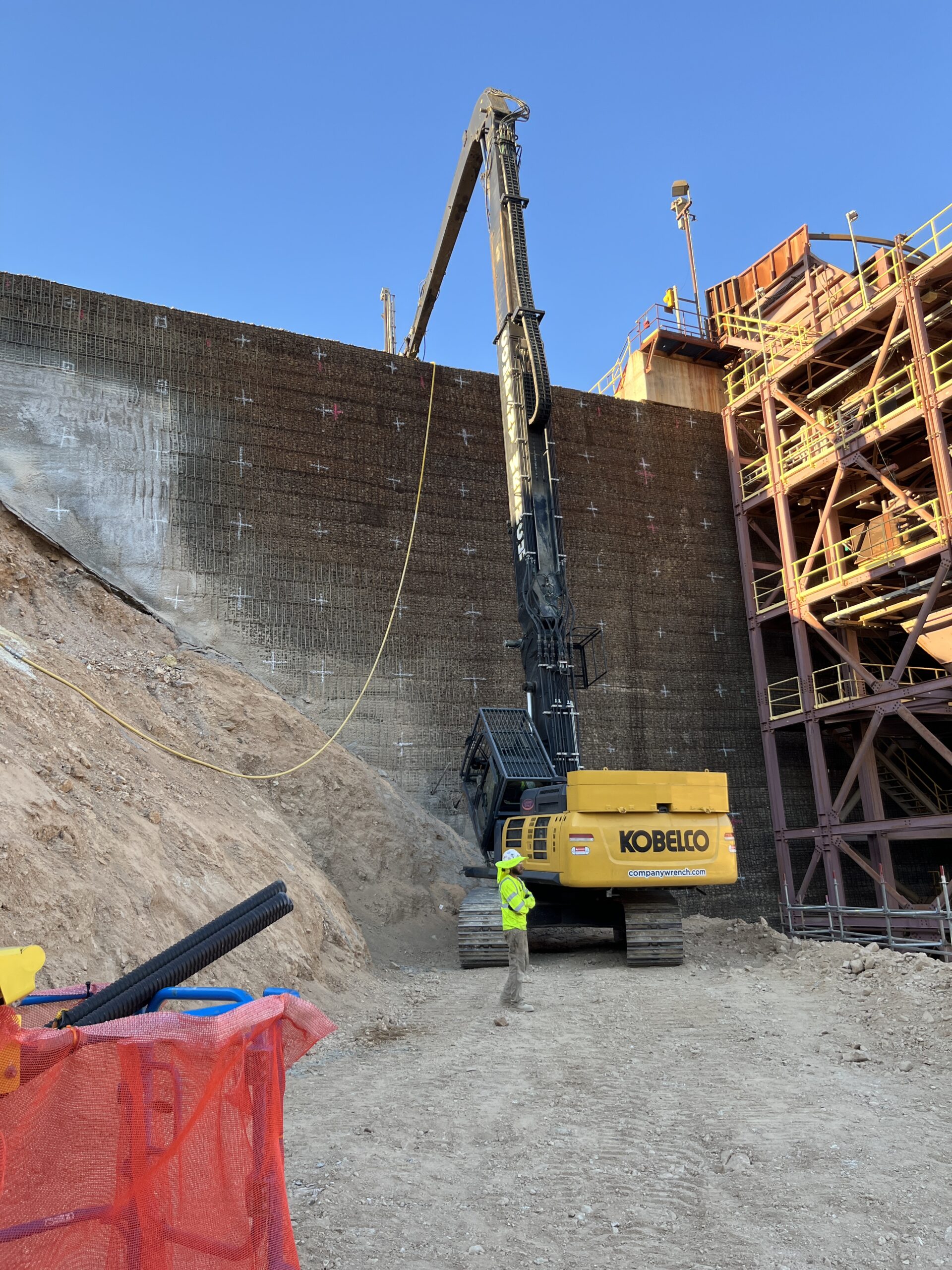 High-reach drill stabilizing MSE wall.