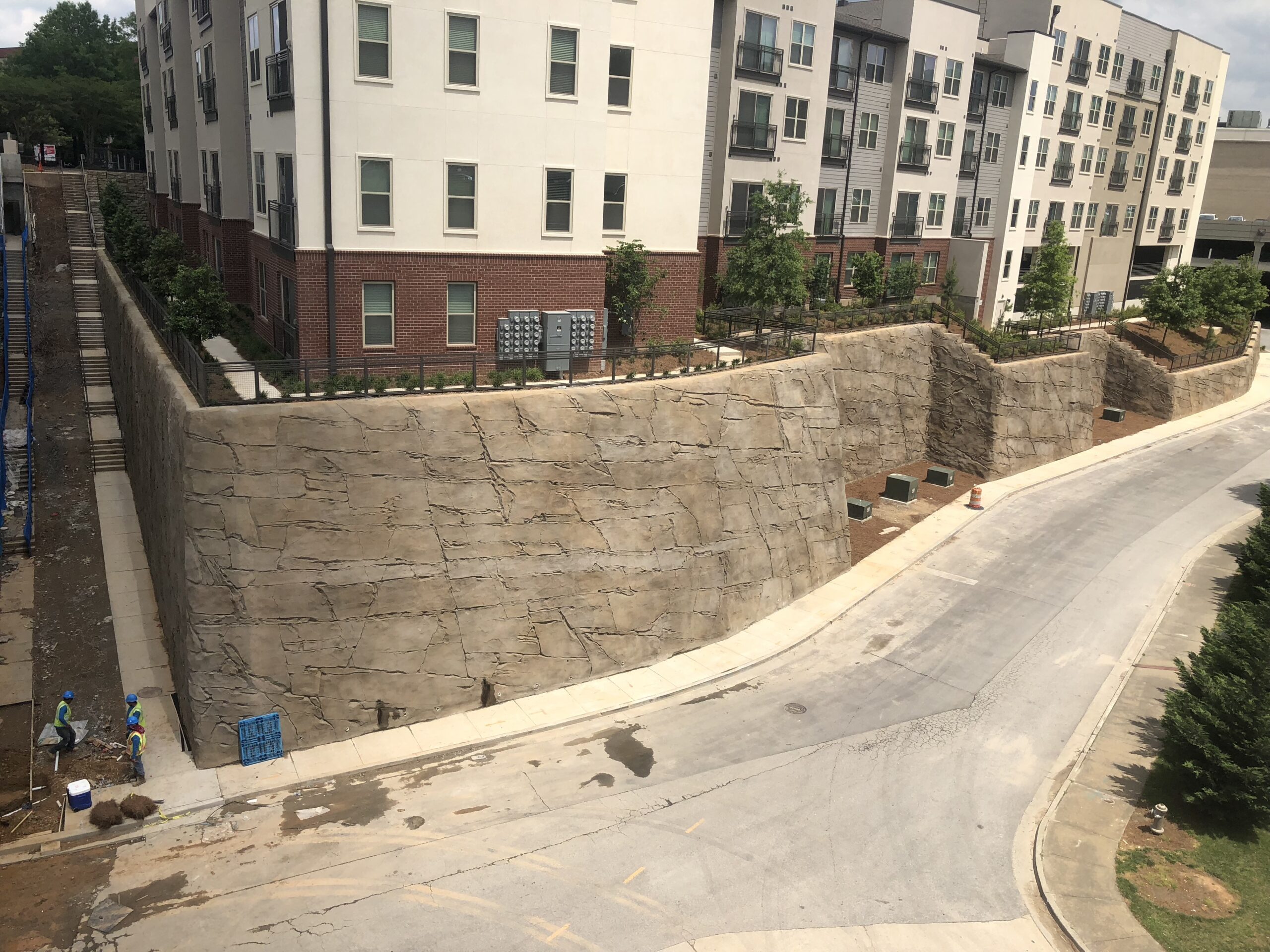 Sculpted shotcrete MSE walls providing slope support beside a multi-story building.