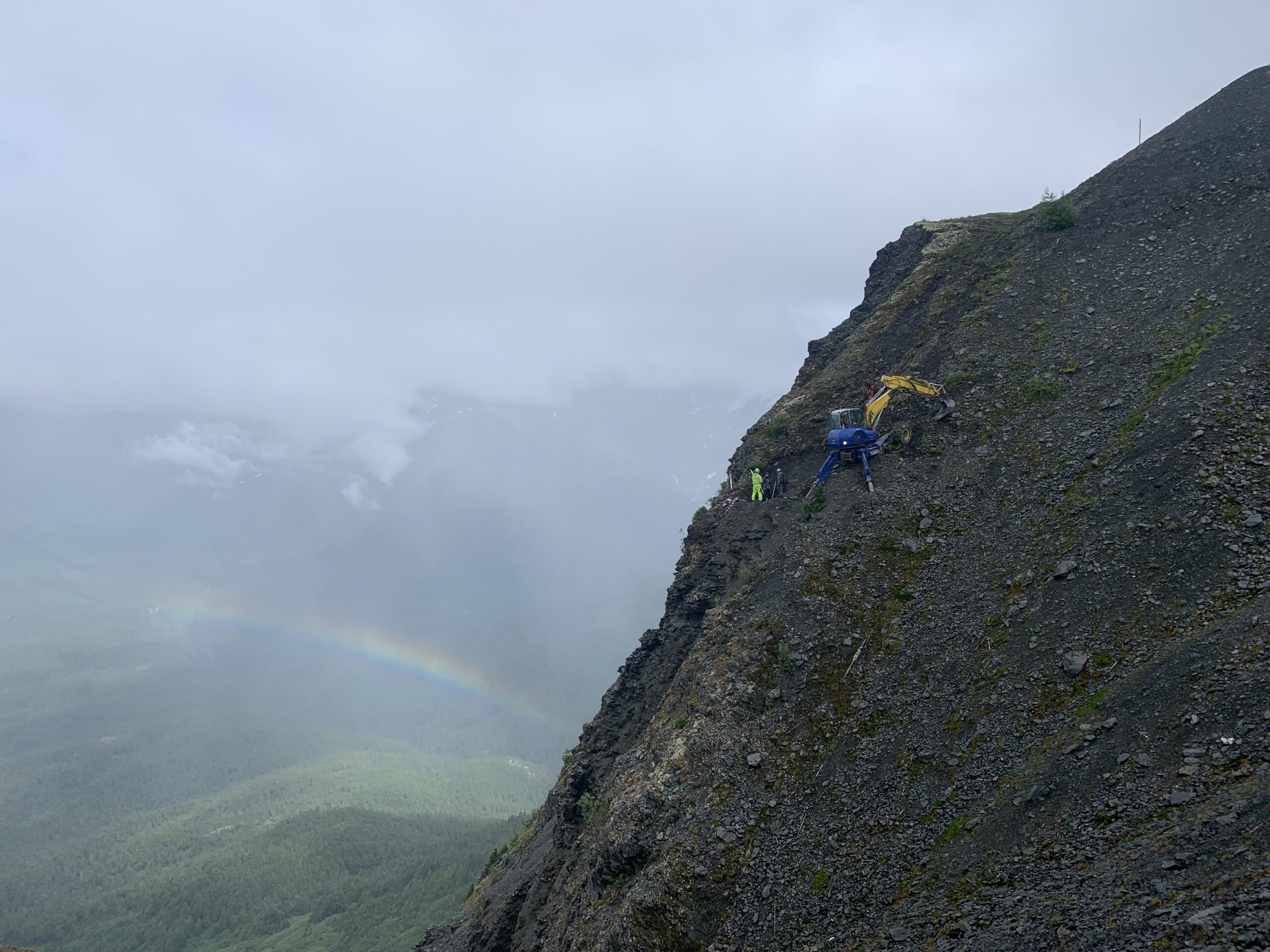Spider excavator operating on an extremely steep rocky mountainside.