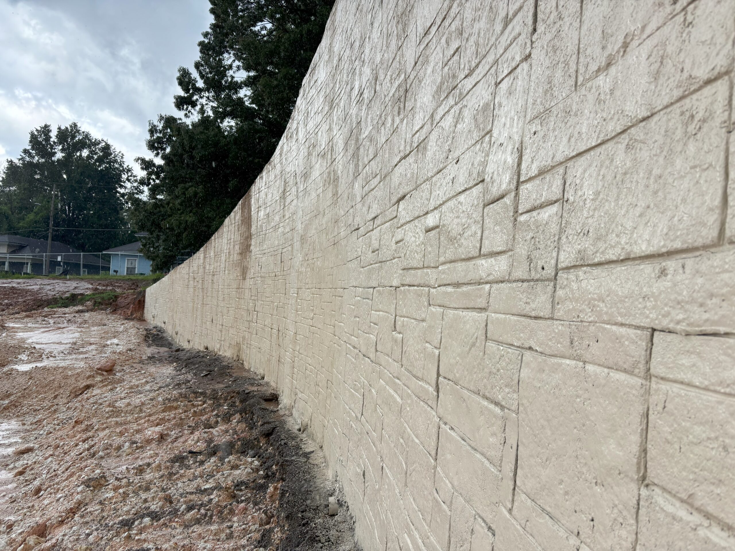 Light-colored shotcrete wall with a stamped ashlar stone pattern.