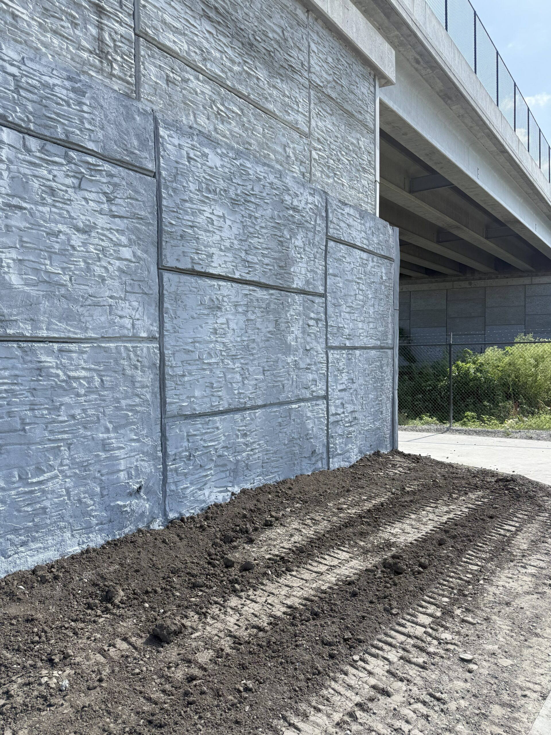 Gray shotcrete wall with large rectangular stamped ashlar pattern.