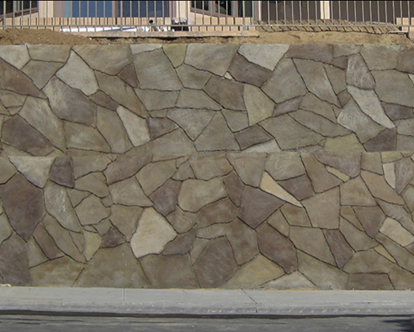 Shotcrete wall with a hand-carved stone finish, stained in multiple earthy tones.