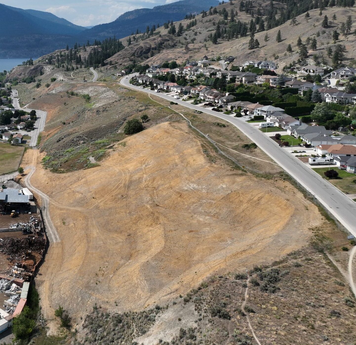 Slope on the slide of a hill with neighborhood below and lake the background