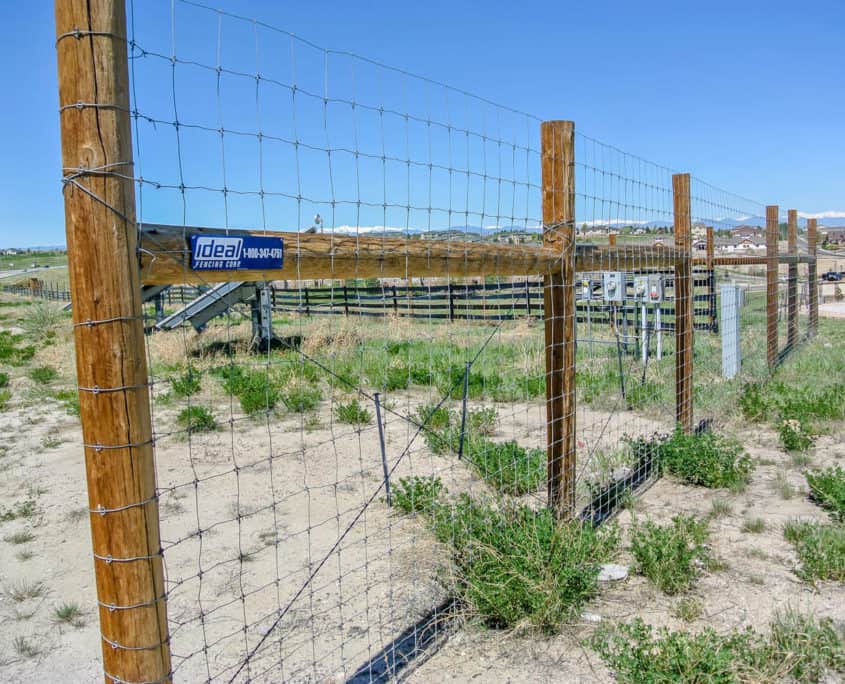 Ideal Fencing wire field fence with wood posts and barbed wire top strand on rural property
