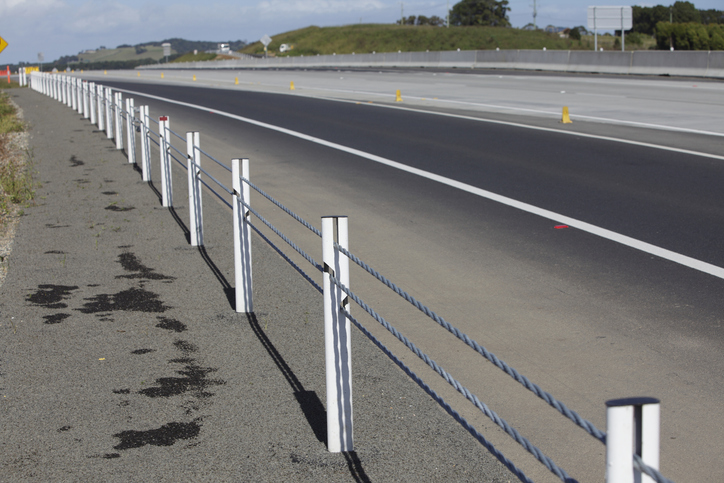 Workers installing highway guardrail on road shoulder
