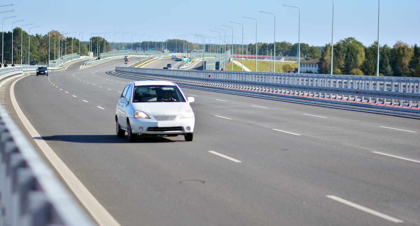 Car driving on modern multi-lane highway with galvanized w-beam guardrail median barrier
