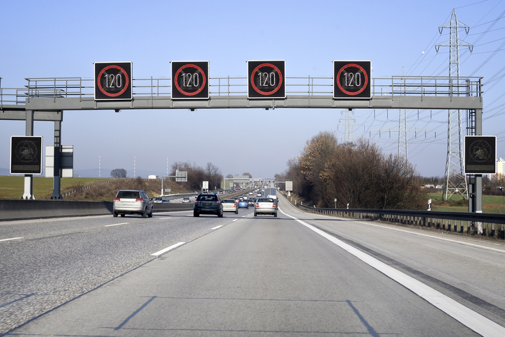 Overhead sign support gantry spanning highway with four 120 km/h speed limit signs