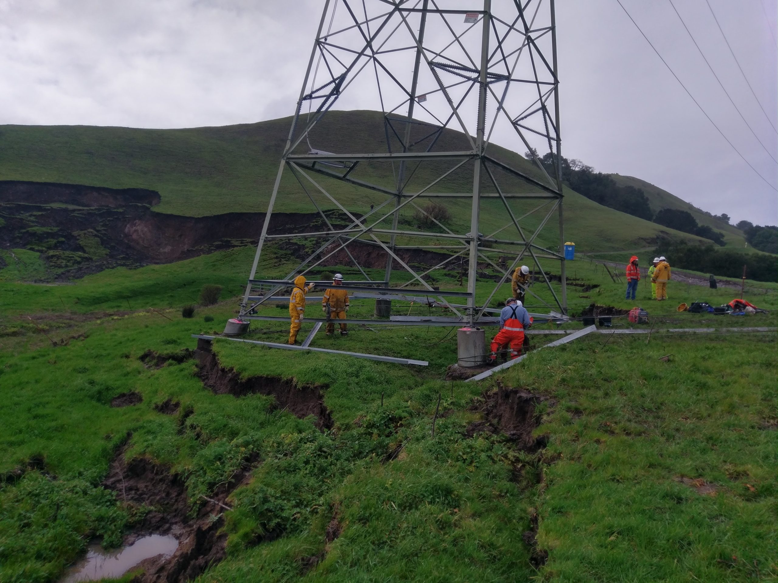 Workers reinforce a transmission tower base.