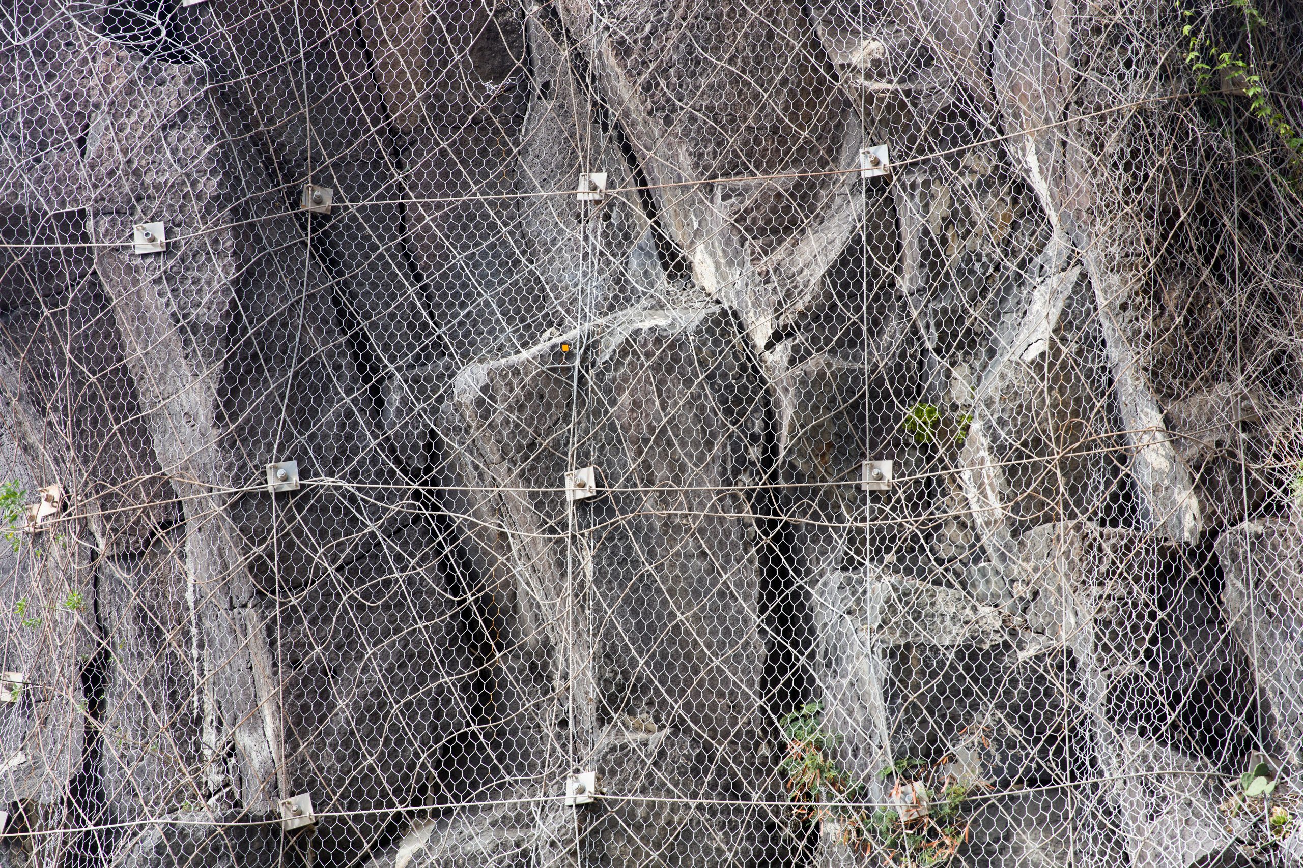 Closeup of slope of the mountain with a rockfall protection net preventing rocks falling on the road