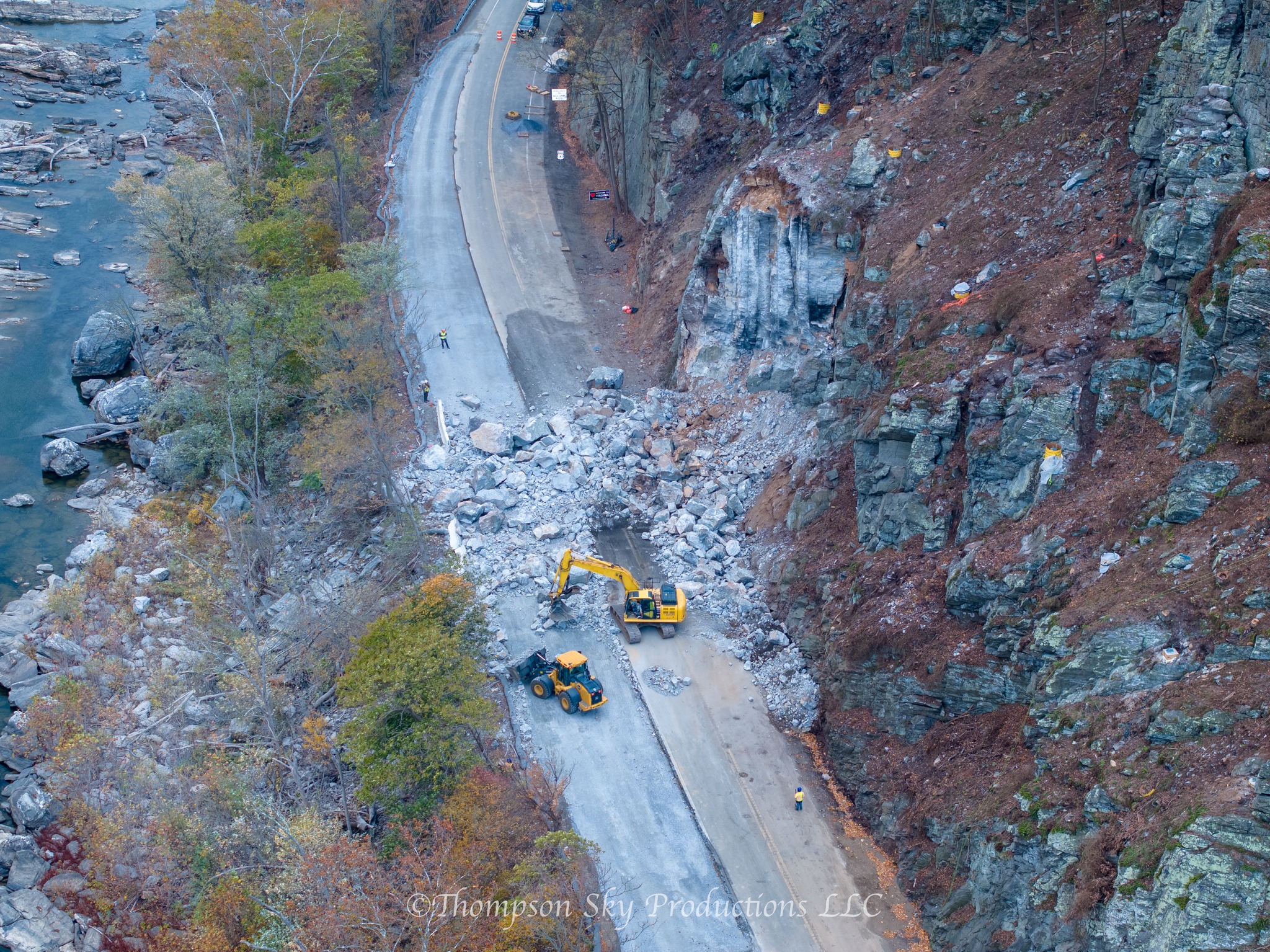 Aerial view of excavators clearing large boulders from a rockfall that blocked a road.