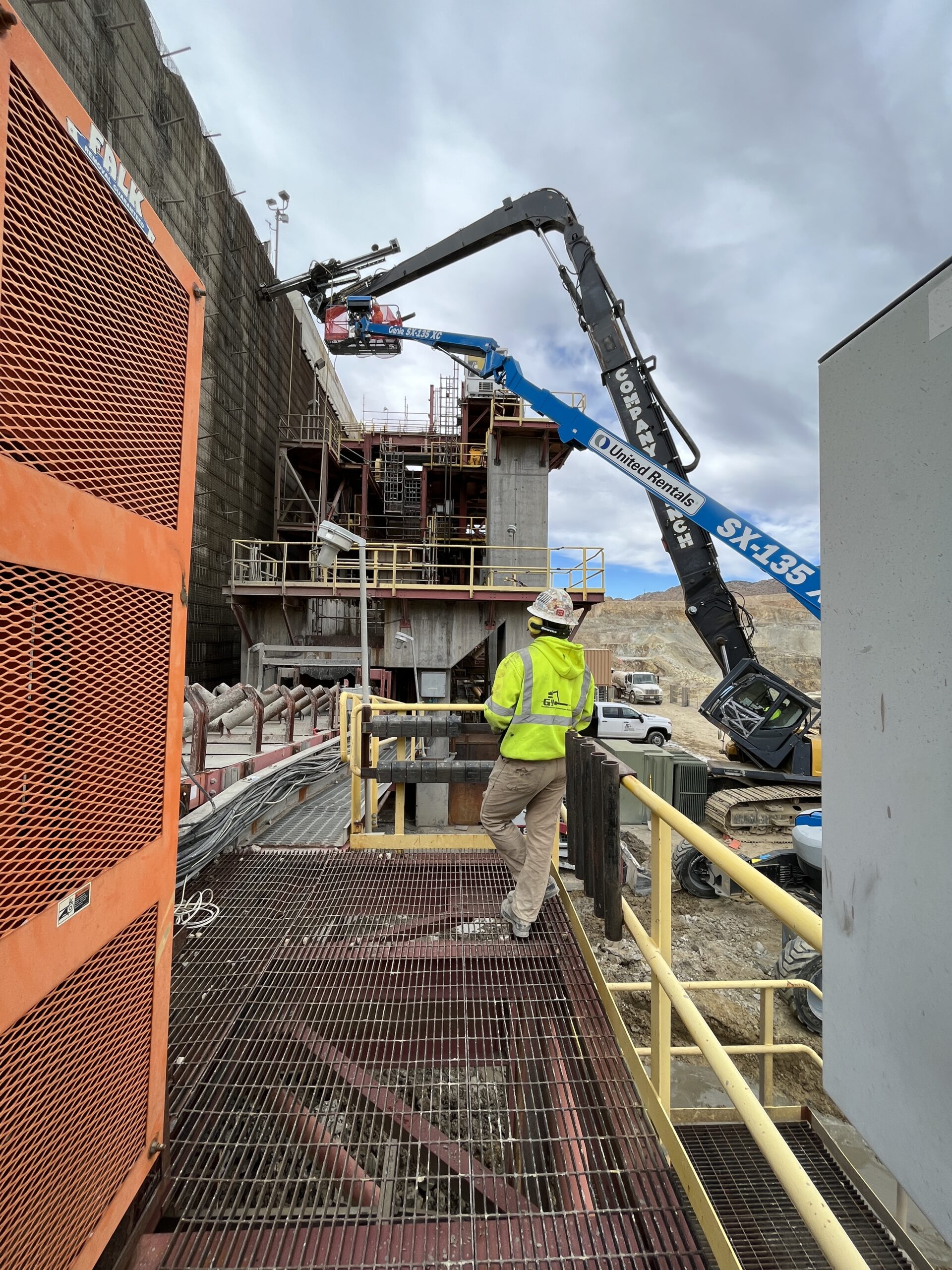 Worker oversees high-reach drilling for MSE wall stabilization.