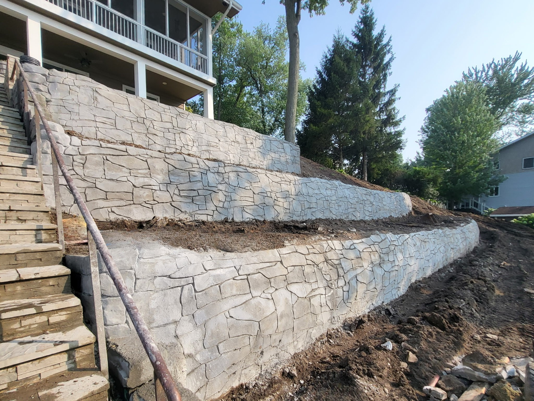 Tiered retaining wall with hand-carved stone-patterned shotcrete finish.