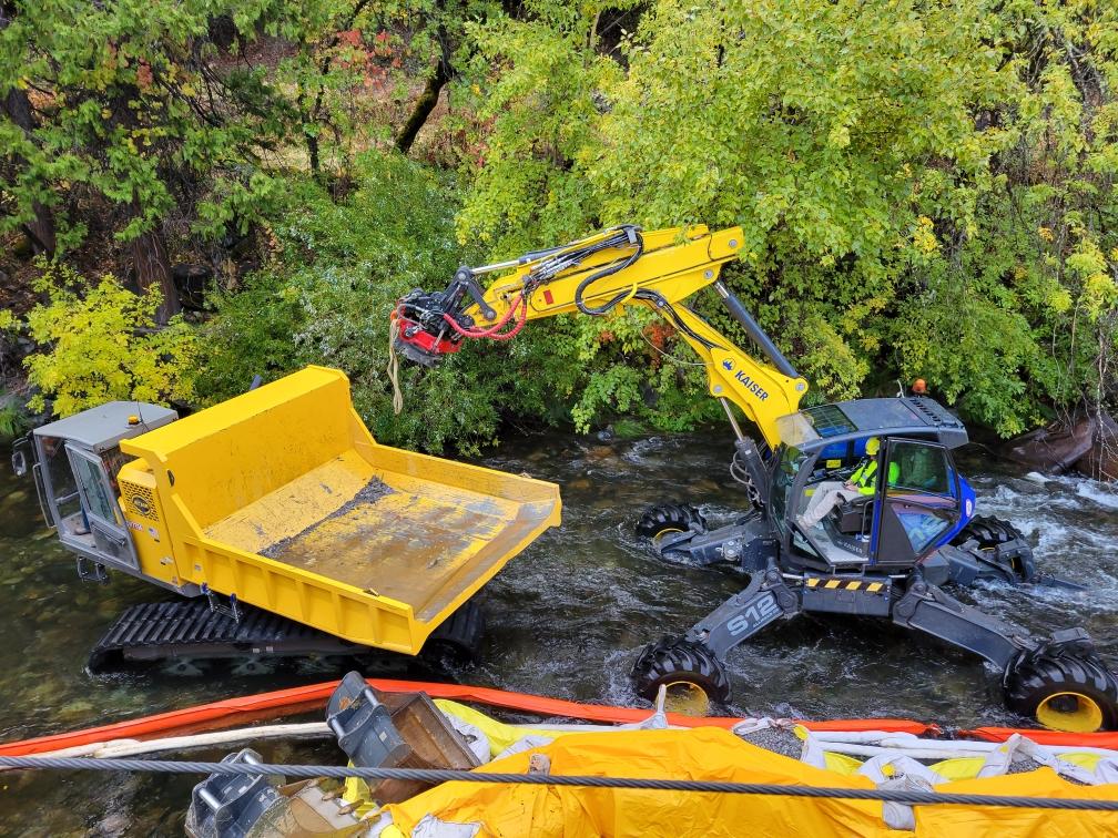Spider excavator removing debris from river.