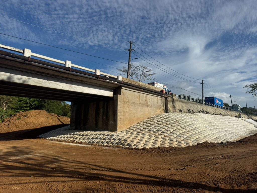 Stabilizing A Bridge with reinforced shotcrete soil nail walls, self-drilling and vertical soil nails, grouted columns installed through the existing pavement, drainage improvements, and erosion-control measures